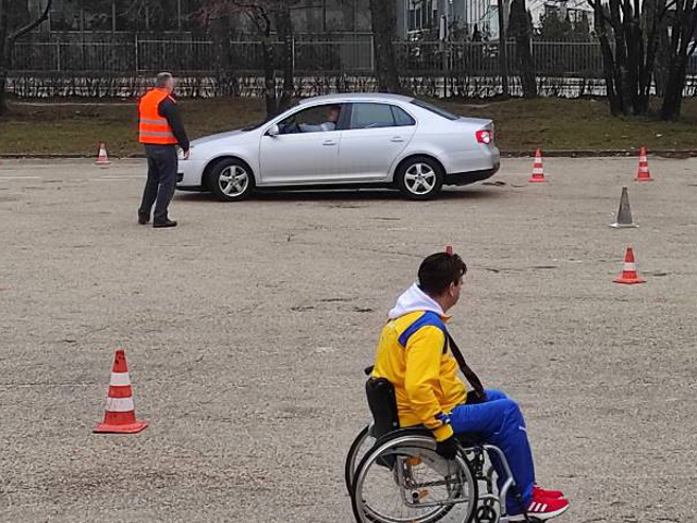 Natjecatelj u kolicima i automobil u pozadini.